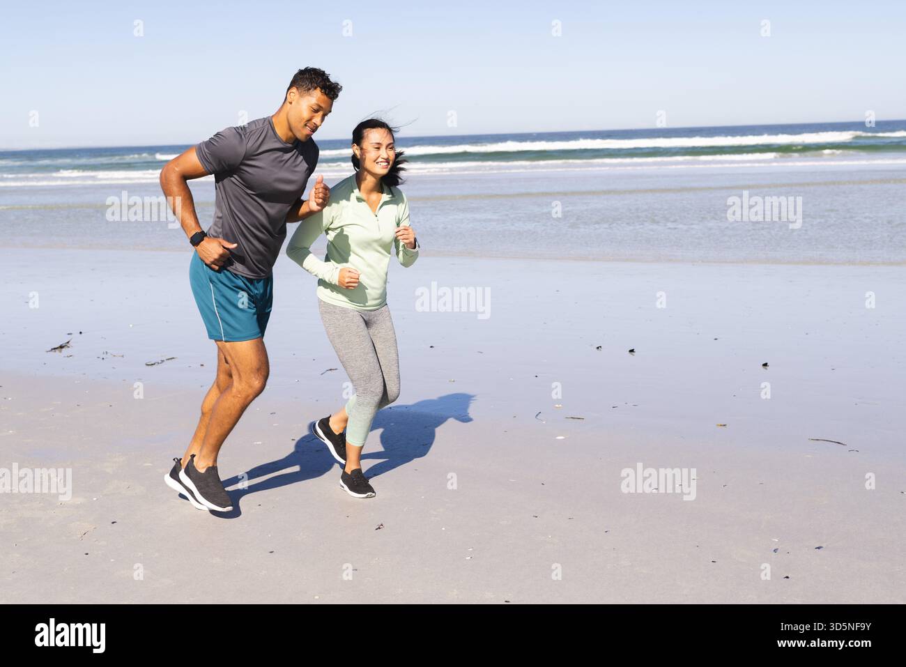 Coppie che fanno jogging sulla spiaggia, si godono gli esercizi mattutini e la fresca brezza dell'oceano, spazio per fotocopie Foto Stock