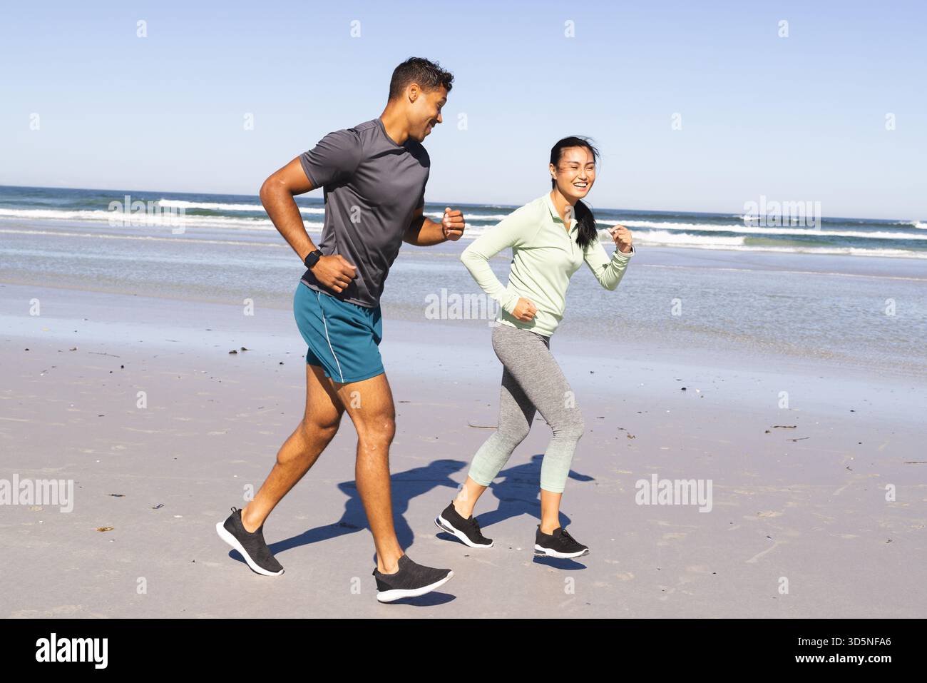 Coppia che fa jogging sulla spiaggia, si fa esercizio mattutino e si respira la fresca brezza dell'oceano Foto Stock