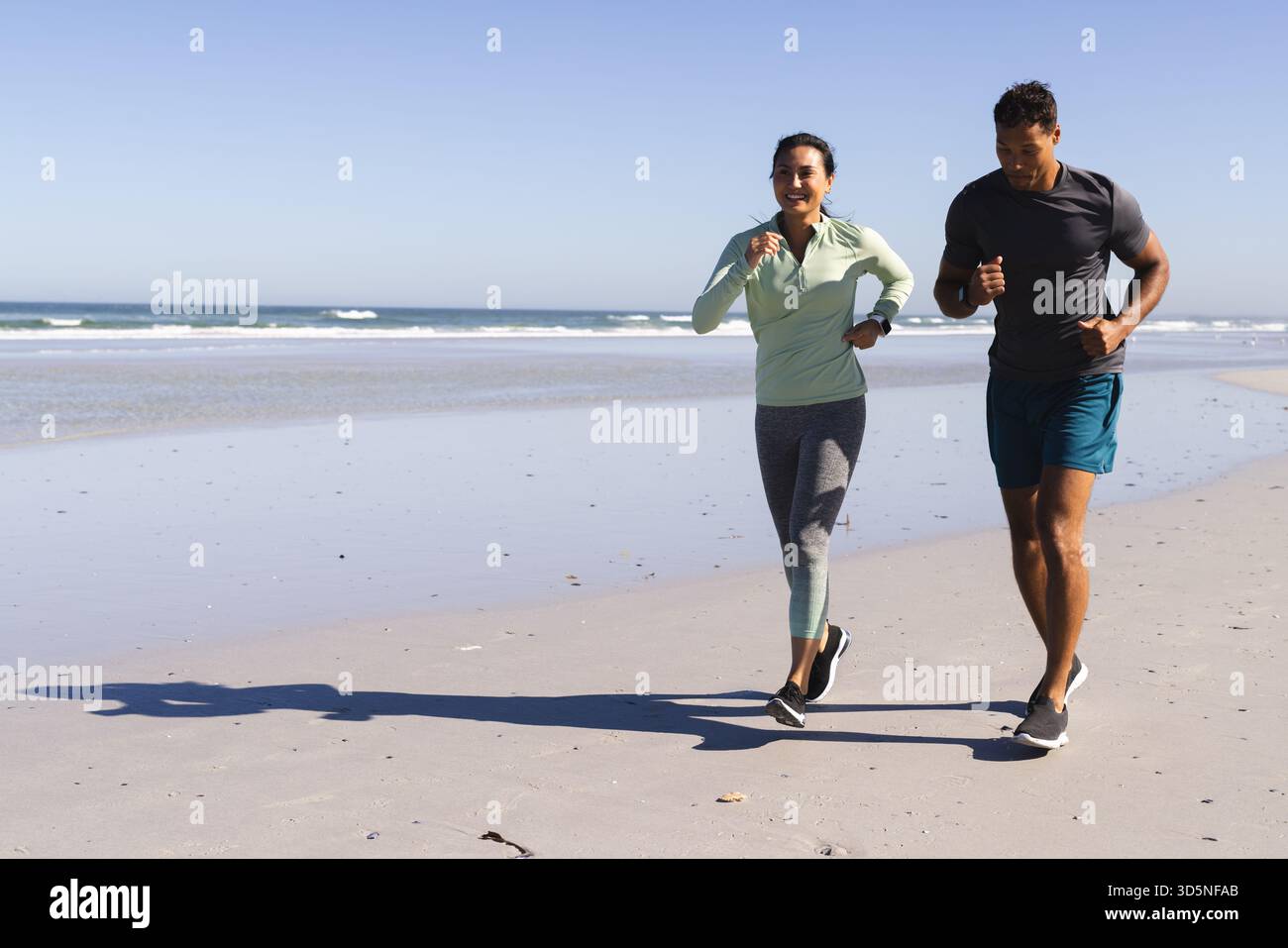 Jogging sulla spiaggia, coppie che si allenano vicino all'oceano con la luce del mattino, spazio per fotocopie Foto Stock