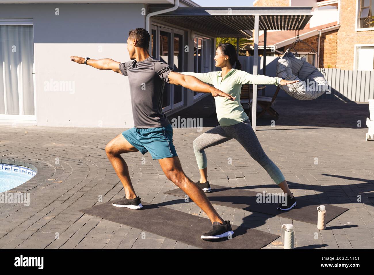 Coppia che pratica yoga all'aperto sui tappetini, mentre si fa esercizio mattutino insieme Foto Stock