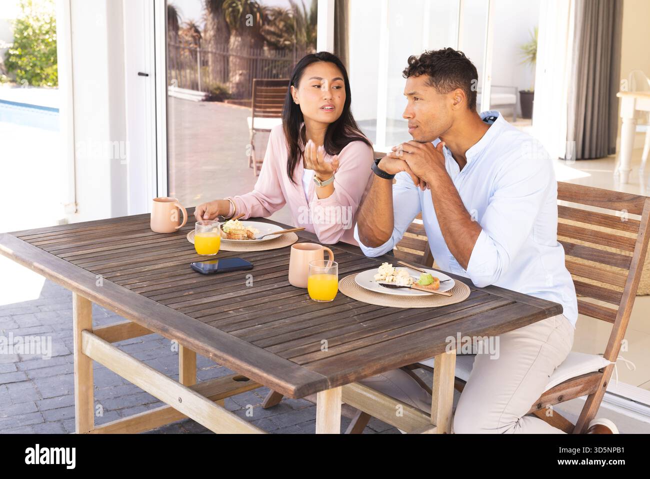 La coppia si è gustata la colazione sul patio, discutendo i piani e sorseggiando succo d'arancia Foto Stock