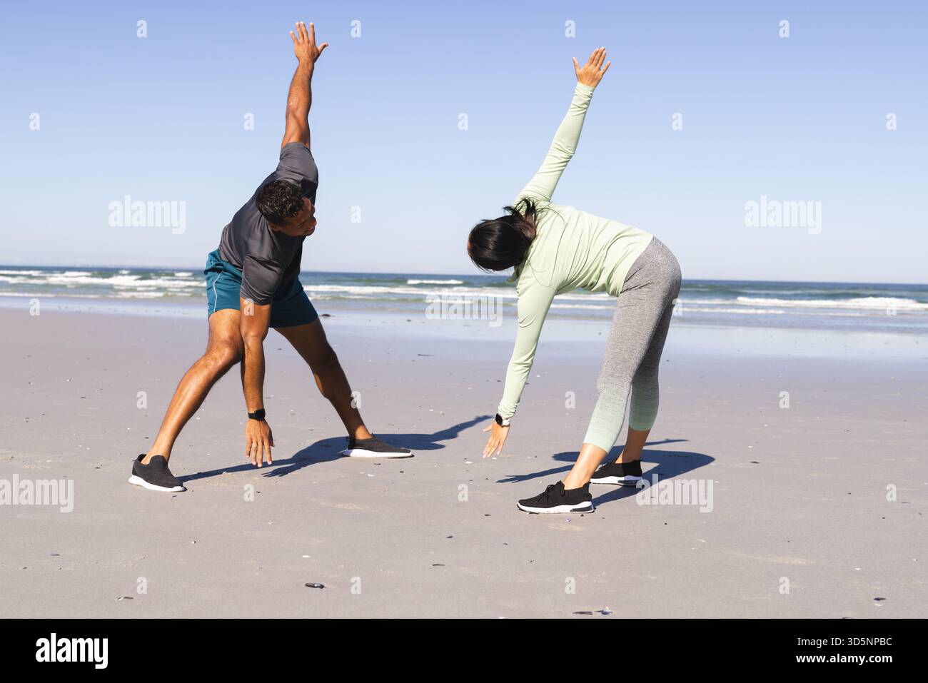 Coppia che si allenano sulla spiaggia, si allungano e si allenano all'aperto insieme Foto Stock