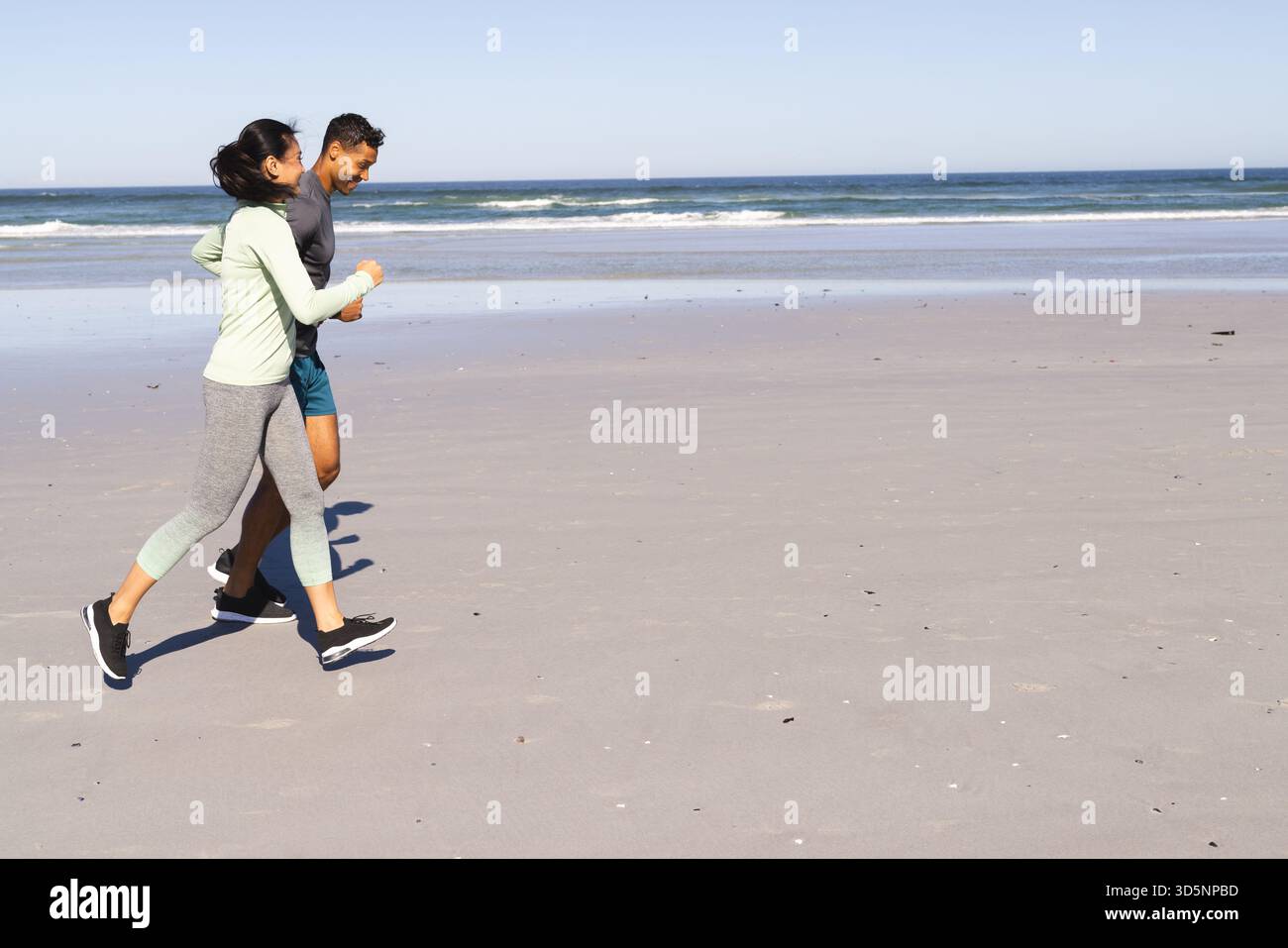 Diverse coppie che fanno jogging lungo la spiaggia sabbiosa all'alba, abbracciano la tranquilla brezza dell'oceano, spazio fotocopie Foto Stock