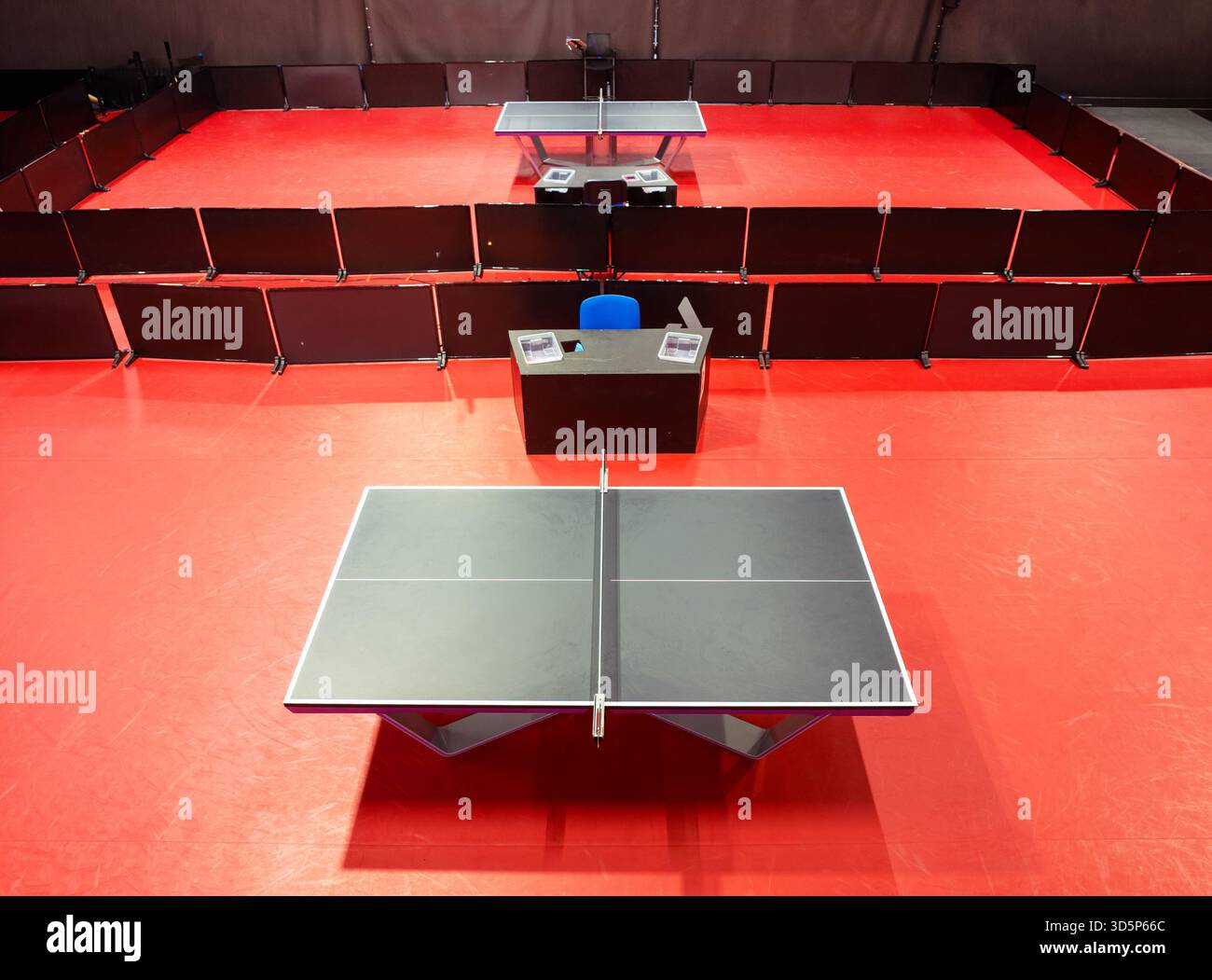 Due tavoli da ping pong o da ping pong neri sono disposti su un piano rosso arancione dello stadio del campo coperto per le competizioni Foto Stock