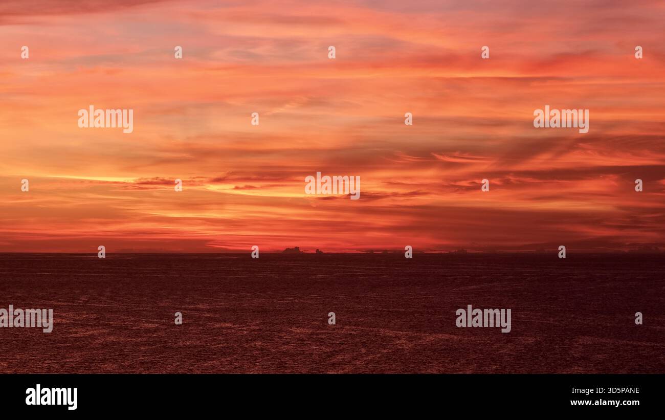 La vista aerea di un tramonto infuocato con sfumature color cremisi e oro dipinge il cielo sopra il tranquillo orizzonte di St. Pete Beach, Florida, Stati Uniti. Foto Stock