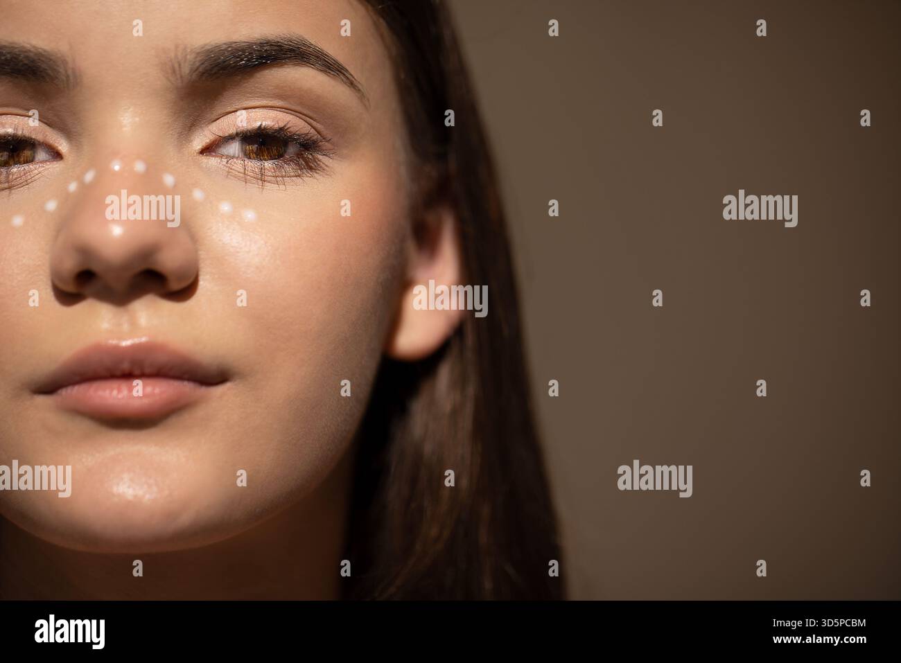 Primo piano di una giovane donna con punti decorativi per il viso, che trasudano fiducia e bellezza, su uno sfondo morbido e neutro che migliora la sua caratteristica Foto Stock