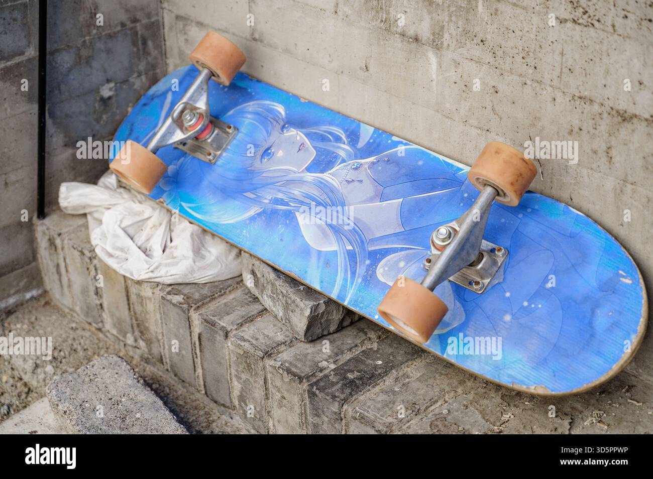 Skateboard con opere d'arte anime lasciate sui mattoni all'angolo di una via hutong di Pechino Foto Stock