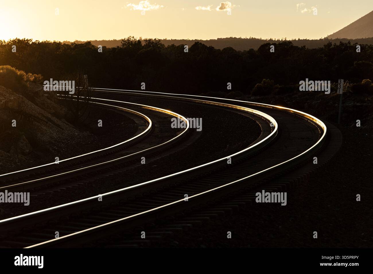 Binari curvi evidenziati da un contrasto elevato al tramonto Foto Stock