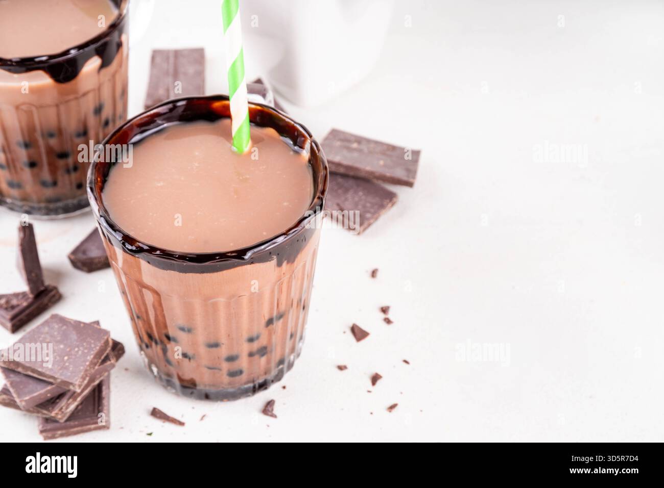 Gustoso tè caldo con bolle di cioccolata. Bevanda calda o fredda di cacao con palline di tapioca e sciroppo di cioccolato fondente, bevanda dolce da dessert su tavolo bianco con c Foto Stock
