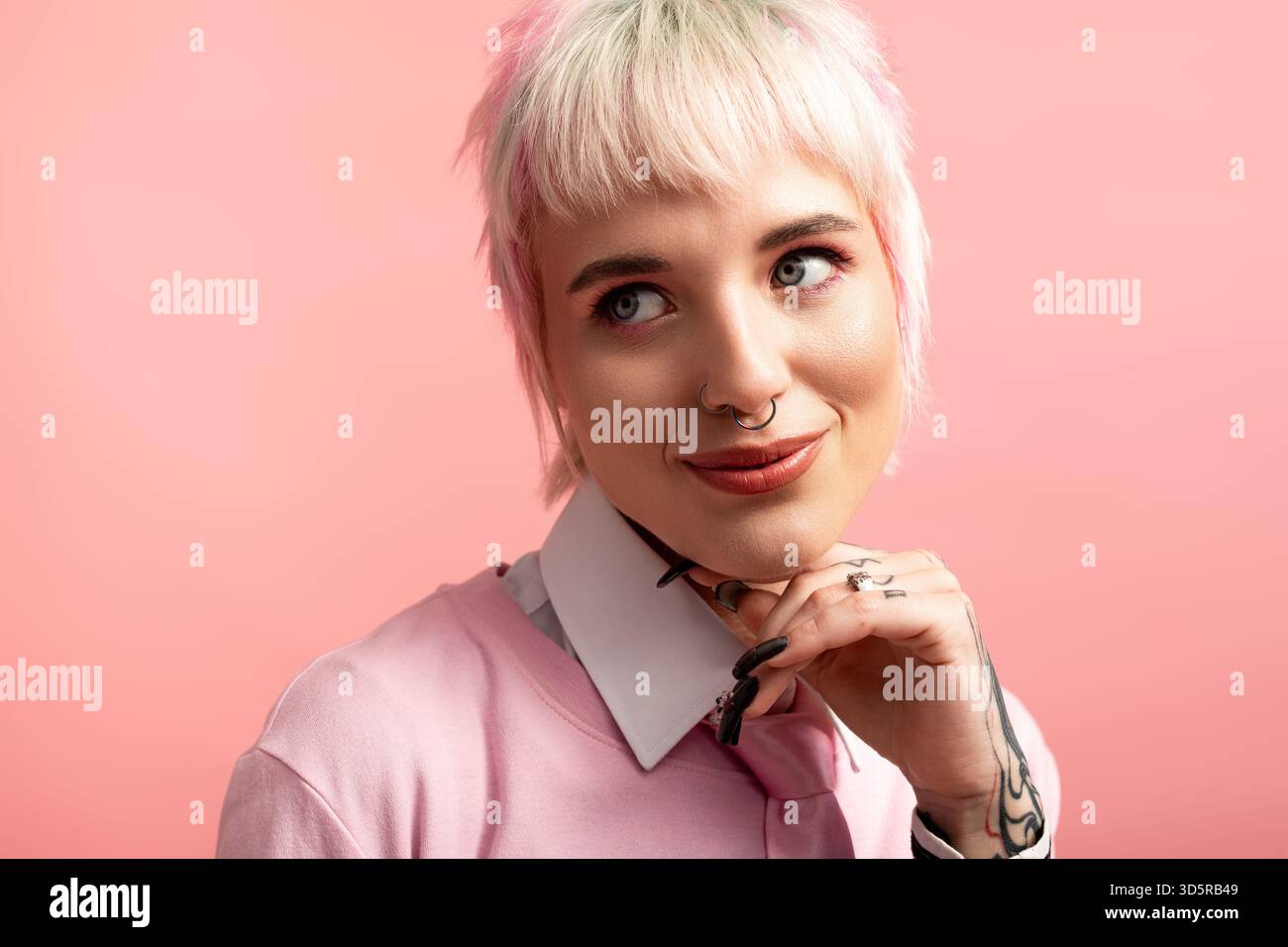 Una giovane e bella donna posa giocosamente con un sorriso sottile, mostrando il suo stile unico. Foto Stock