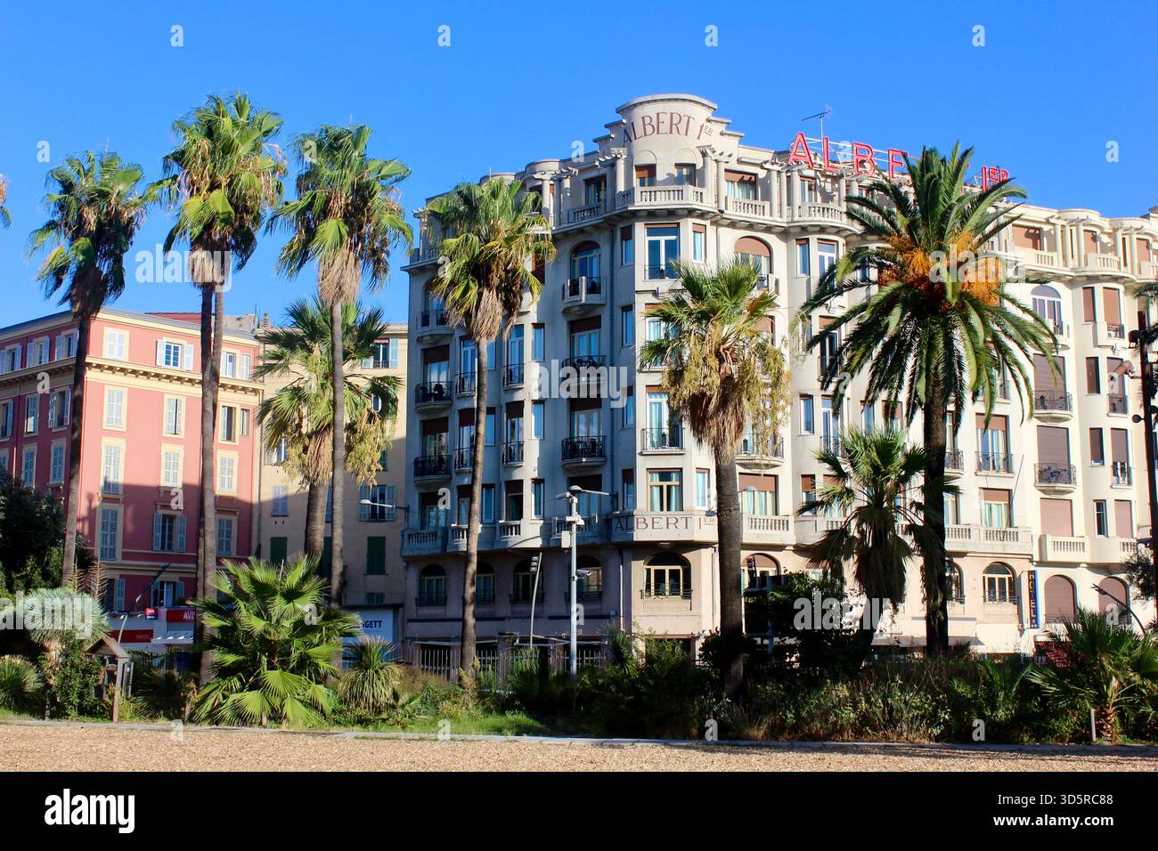 Storico edificio mediterraneo con alte palme a Nizza, Francia, sotto un cielo azzurro. Elegante architettura costiera nella Costa Azzurra. Foto Stock