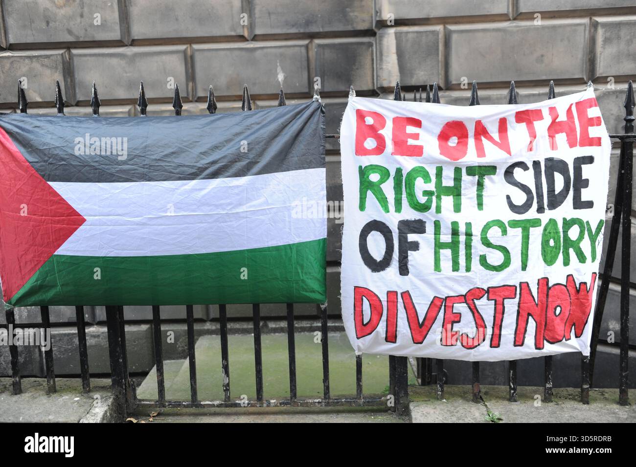 EDIMBURGO, SCOZIA – 17 novembre 2025: Uno stendardo e la bandiera della Palestina visti su una recinzione. I membri della University and College Union (UCU) presso l'Università di Edimburgo sono solidali sulle linee di picchetto in importanti ingressi del campus durante gli orari di apertura di un'azione industriale di tre giorni che inizia il 17 novembre 2025 a Edimburgo, Scozia, protestando contro un'iniziativa di risparmio di 140 milioni di sterline che potrebbe portare a significative riduzioni del personale, cessazioni obbligatorie e modifiche ai termini di impiego. Le dimostrazioni si svolgono tra le 9:00 e le 12:00 in siti selezionati, con un incontro chiave a. Foto Stock