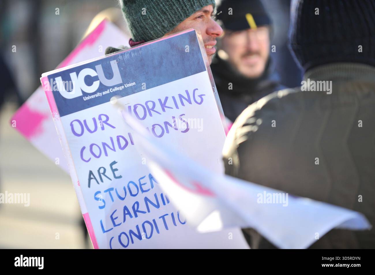 EDIMBURGO, SCOZIA – 17 novembre 2025: Manifestanti visti al picchetto con cartello. I membri della University and College Union (UCU) presso l'Università di Edimburgo sono solidali sulle linee di picchetto in importanti ingressi del campus durante gli orari di apertura di un'azione industriale di tre giorni che inizia il 17 novembre 2025 a Edimburgo, Scozia, protestando contro un'iniziativa di risparmio di 140 milioni di sterline che potrebbe portare a significative riduzioni del personale, cessazioni obbligatorie e modifiche ai termini di impiego. Le dimostrazioni si svolgono tra le 9:00 e le 12:00 in siti selezionati, con un'anticipazione chiave dell'incontro Foto Stock
