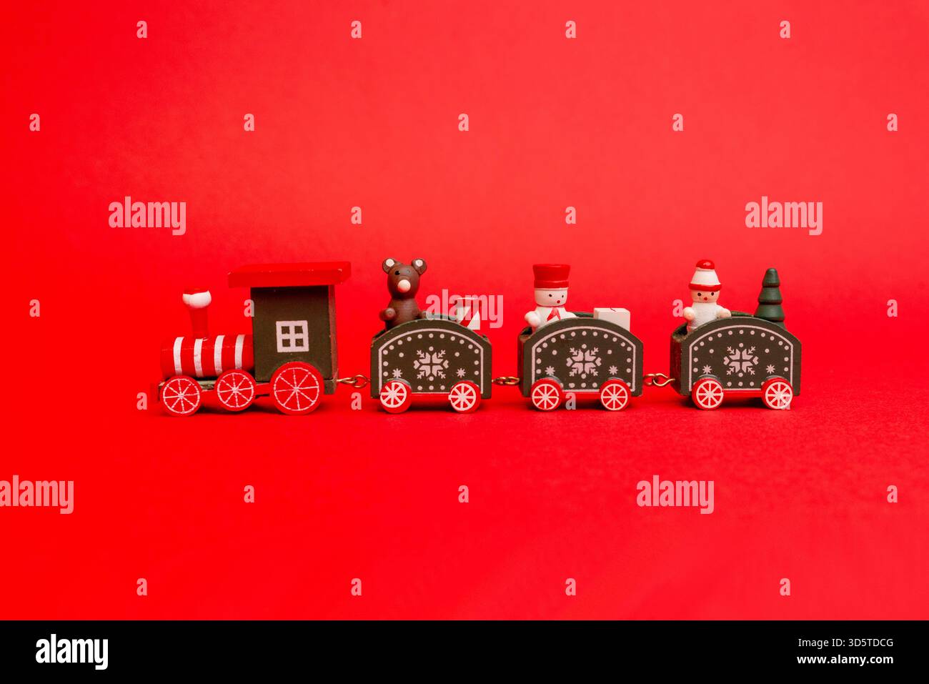 Giocattolo natalizio in legno con minuscoli personaggi natalizi visualizzati su uno sfondo rosso brillante Foto Stock