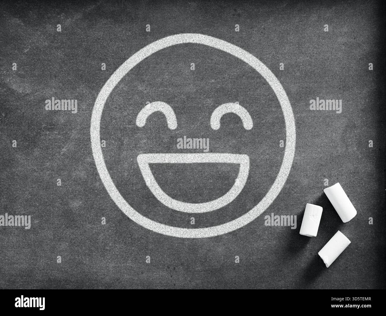Disegno in gesso di un emoji ridendo su una lavagna, che rappresenta la felicità, la positività e le buone vibrazioni nell'istruzione. Foto Stock
