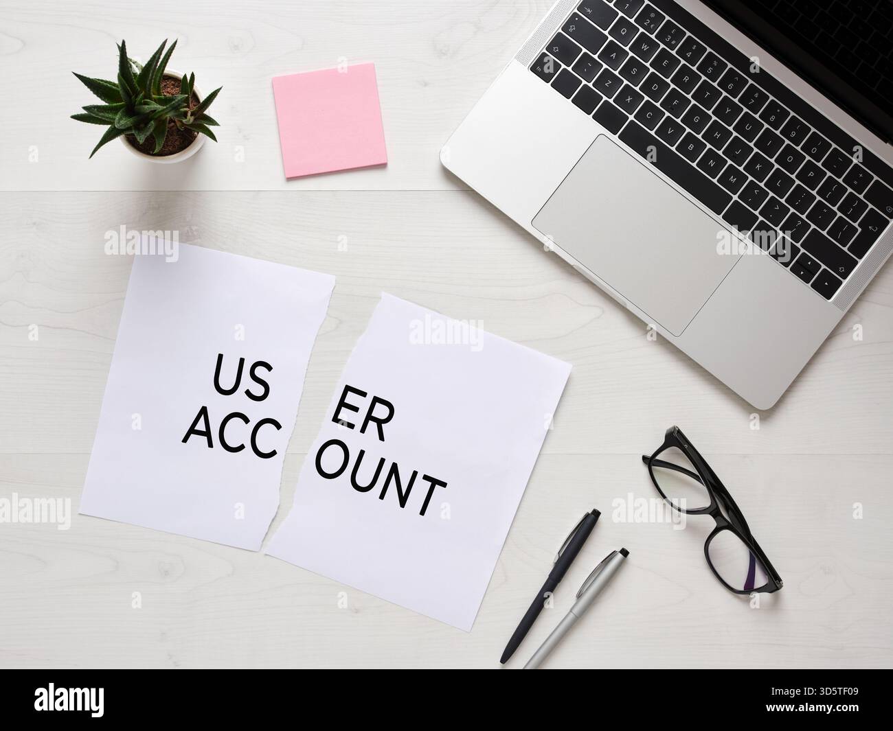 Strappato un foglio di carta con l'account utente di testo accanto al laptop, occhiali e penne su un tavolo bianco, chiudendo il concetto di account Foto Stock