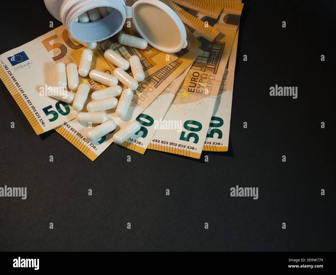 Costi sanitari: Banconote e pillole in euro - capsule bianche versano da una bottiglia aperta su banconote da 50 euro, illustrando l'aumento dei costi Foto Stock