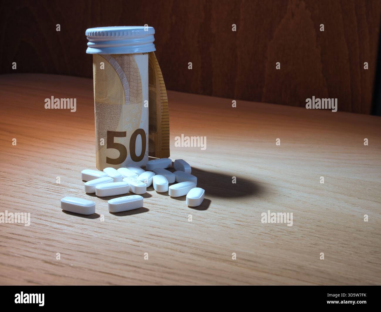 Costi della medicina: 50 Euro Banknote and Pills - Una metafora visiva per il peso finanziario dei farmaci. Una banconota da 50 euro circonda una bottiglia di pillola, sur Foto Stock