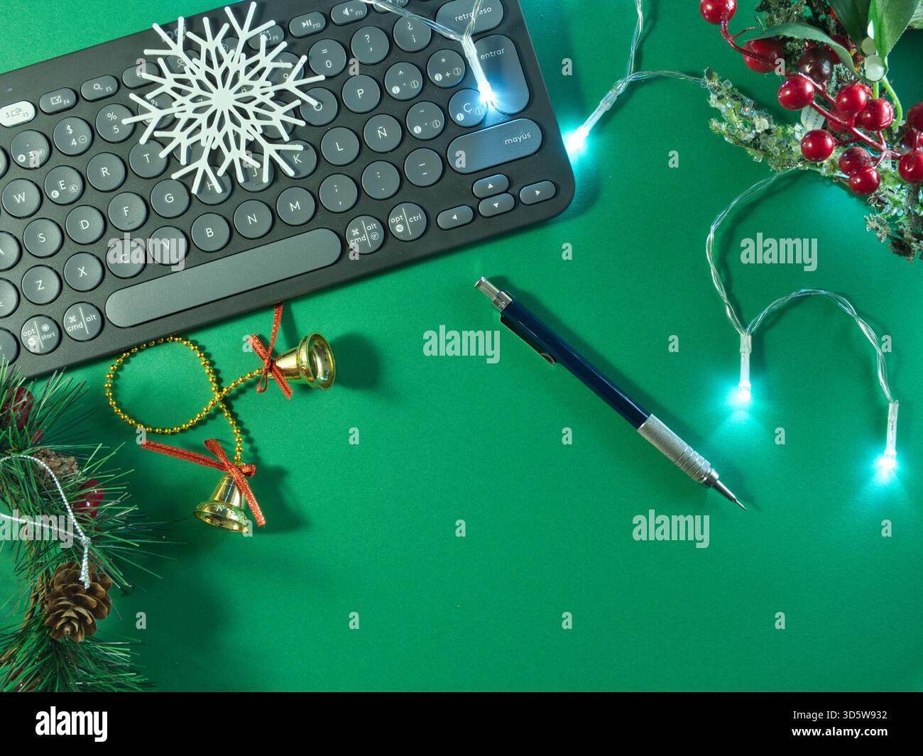 Allestimento per le feste con tastiera - tastiera per computer con decorazioni natalizie e luci fiabesche su sfondo verde vivace, Foto Stock