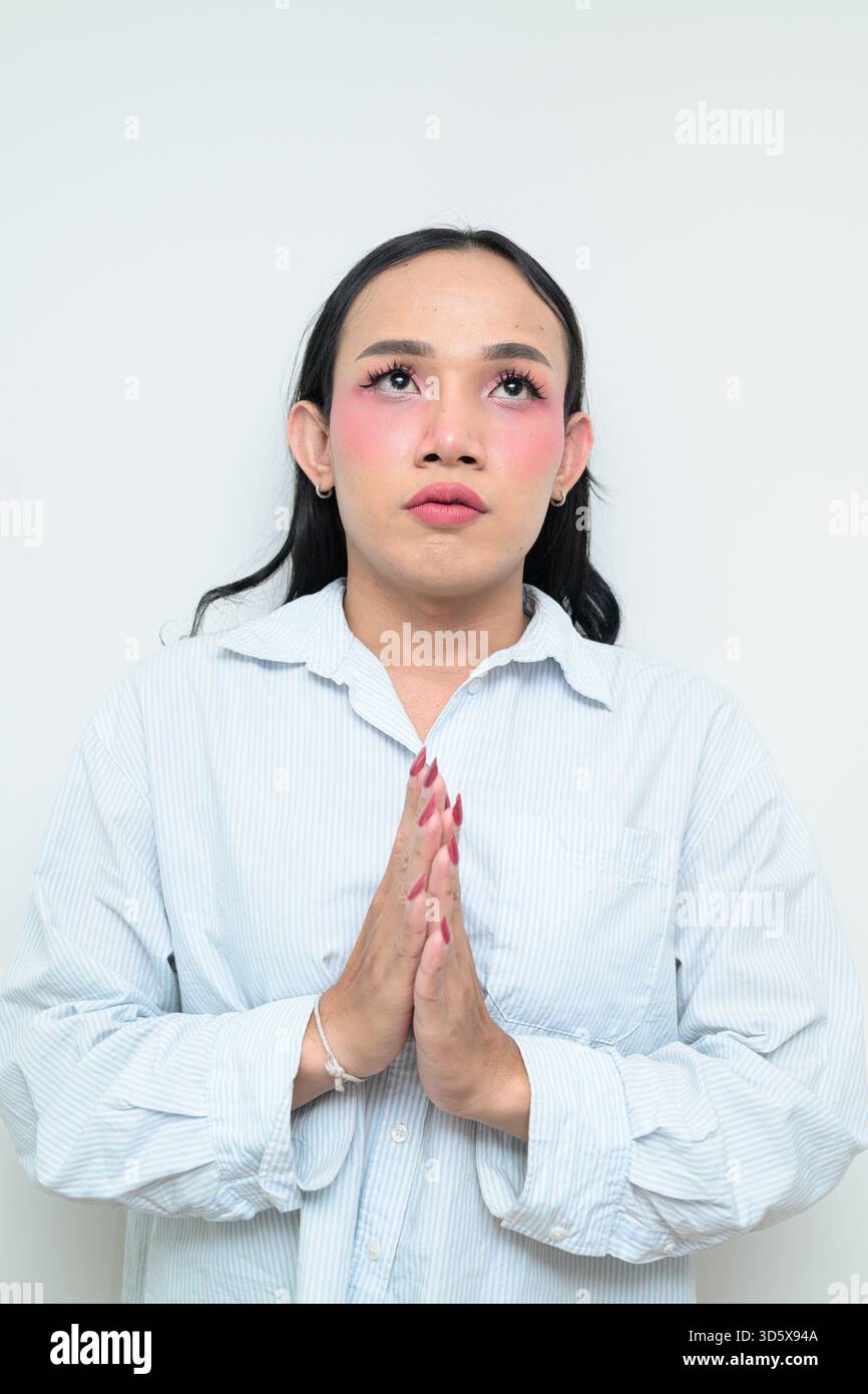 Ritratto in studio di un giovane individuo transgender thailandese con trucco e capelli lunghi. Concetto di espressione di genere, orgoglio LGBTQ e inclusività che mostra un Foto Stock