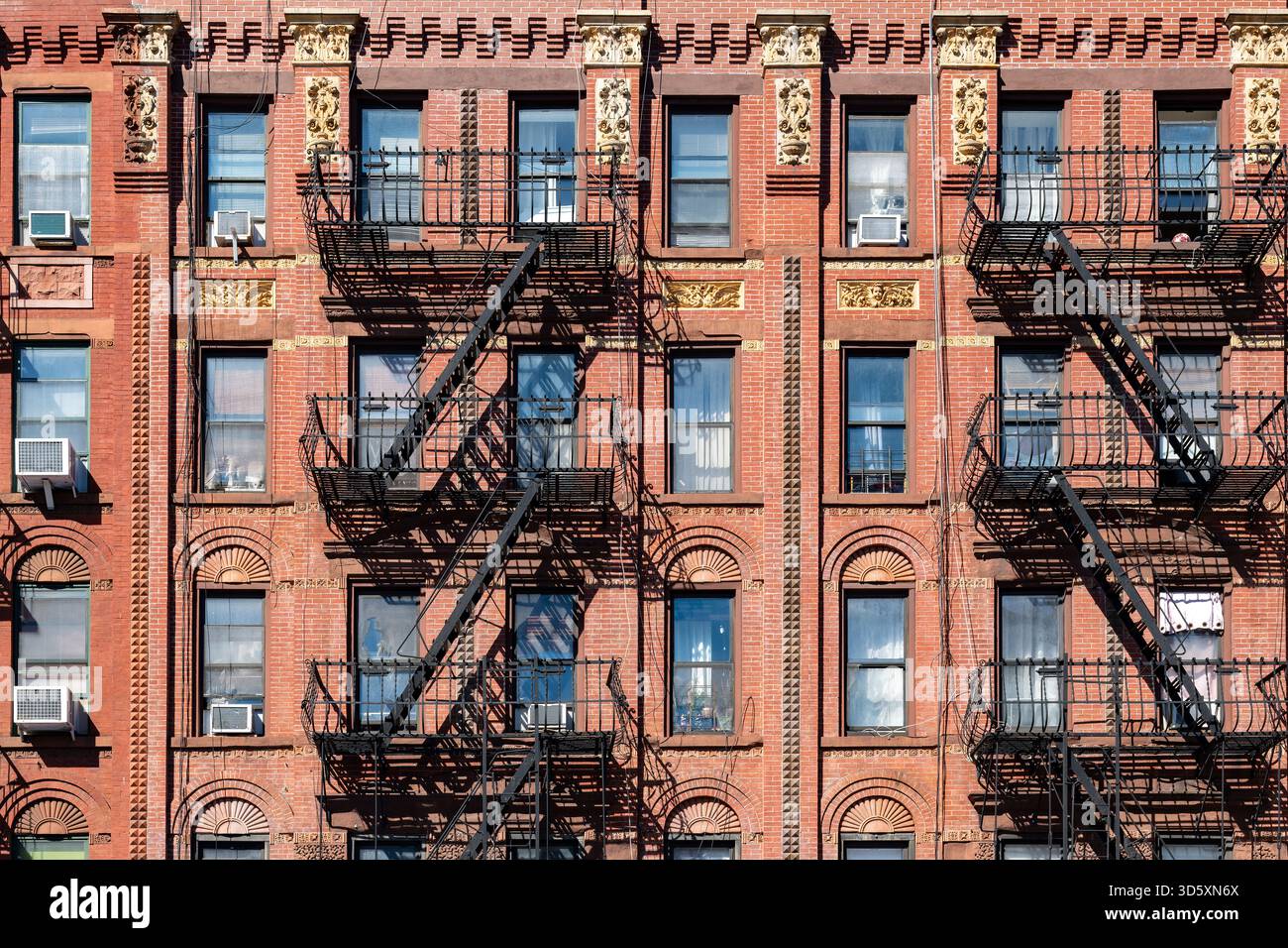 Un primo piano di un tipico edificio residenziale di Harlem con mattoni rossi e dettagli decorativi sulle finestre. Foto Stock