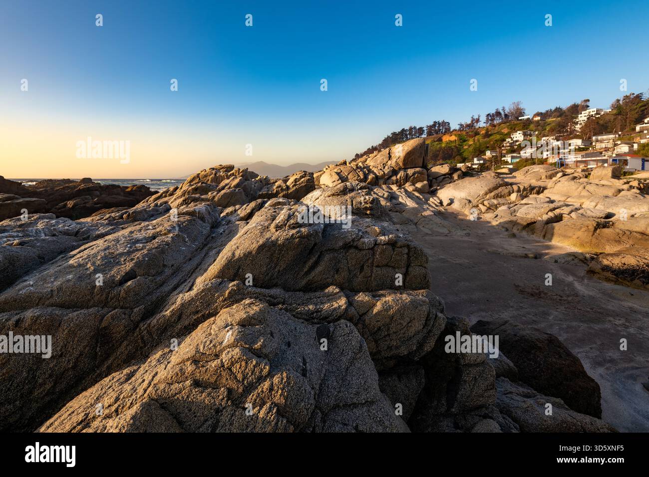 La costa frastagliata e la spiaggia rocciosa della località turistica di Maitencillo nella regione di Valparaíso in Cile, al tramonto. Foto Stock