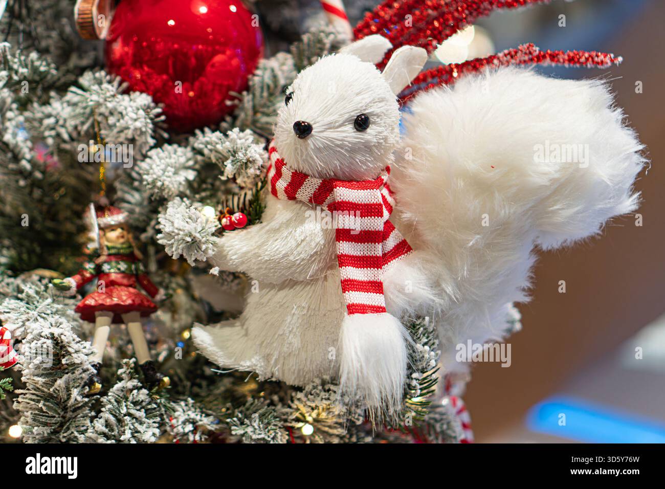 Scena natalizia domestica con un albero posizionato centralmente, adornato con tinsel argentato e baule rosse, Un importante giocattolo per conigli bianco con sciarpa rossa è S Foto Stock