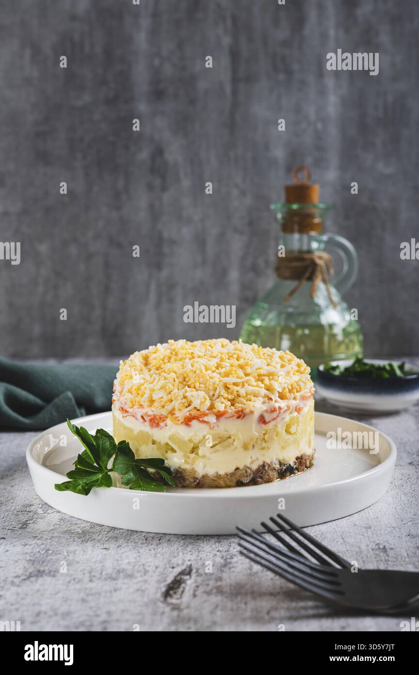Tradizionale insalata a strati con pesce in scatola su un piatto sul tavolo vista verticale Foto Stock