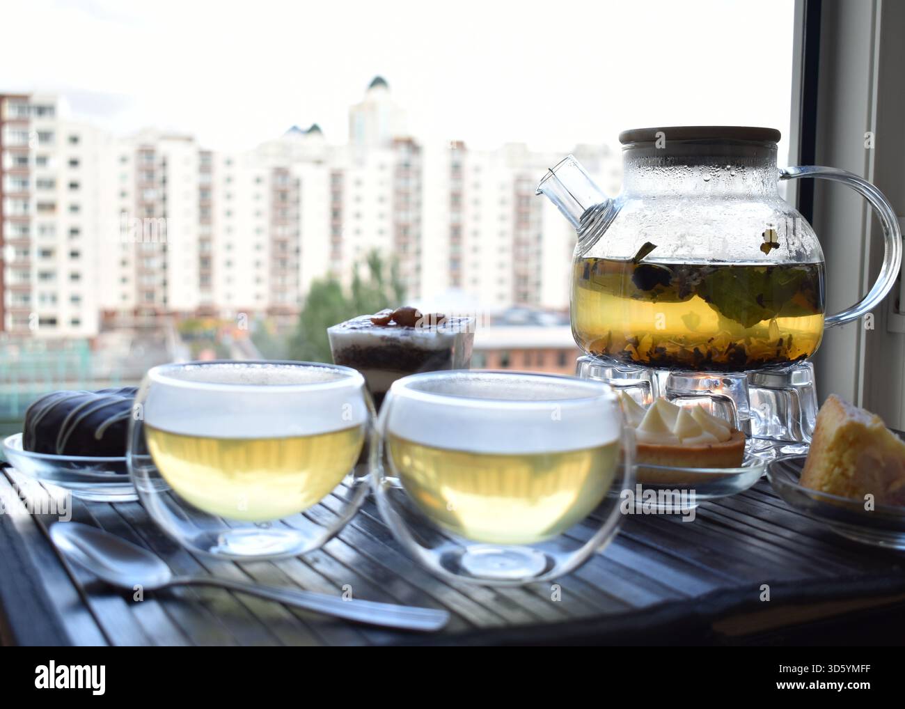 Tazza di tè con pasticcini in vetro trasparente moderno vicino al cortile della città Foto Stock