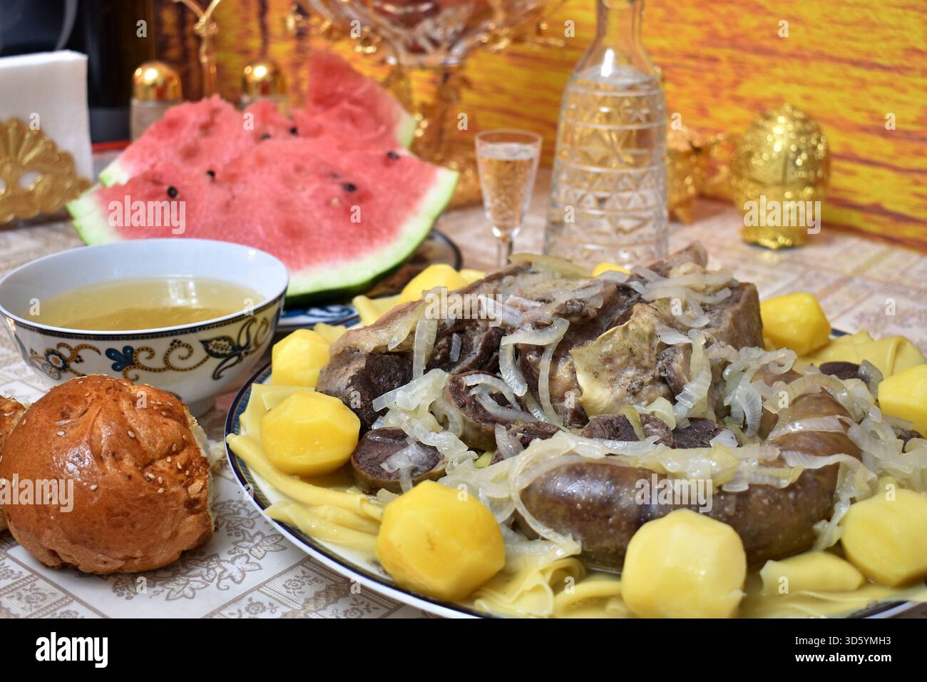 Tradizionale beshbarmak kazako con fette di anguria e decanter di vodka Foto Stock