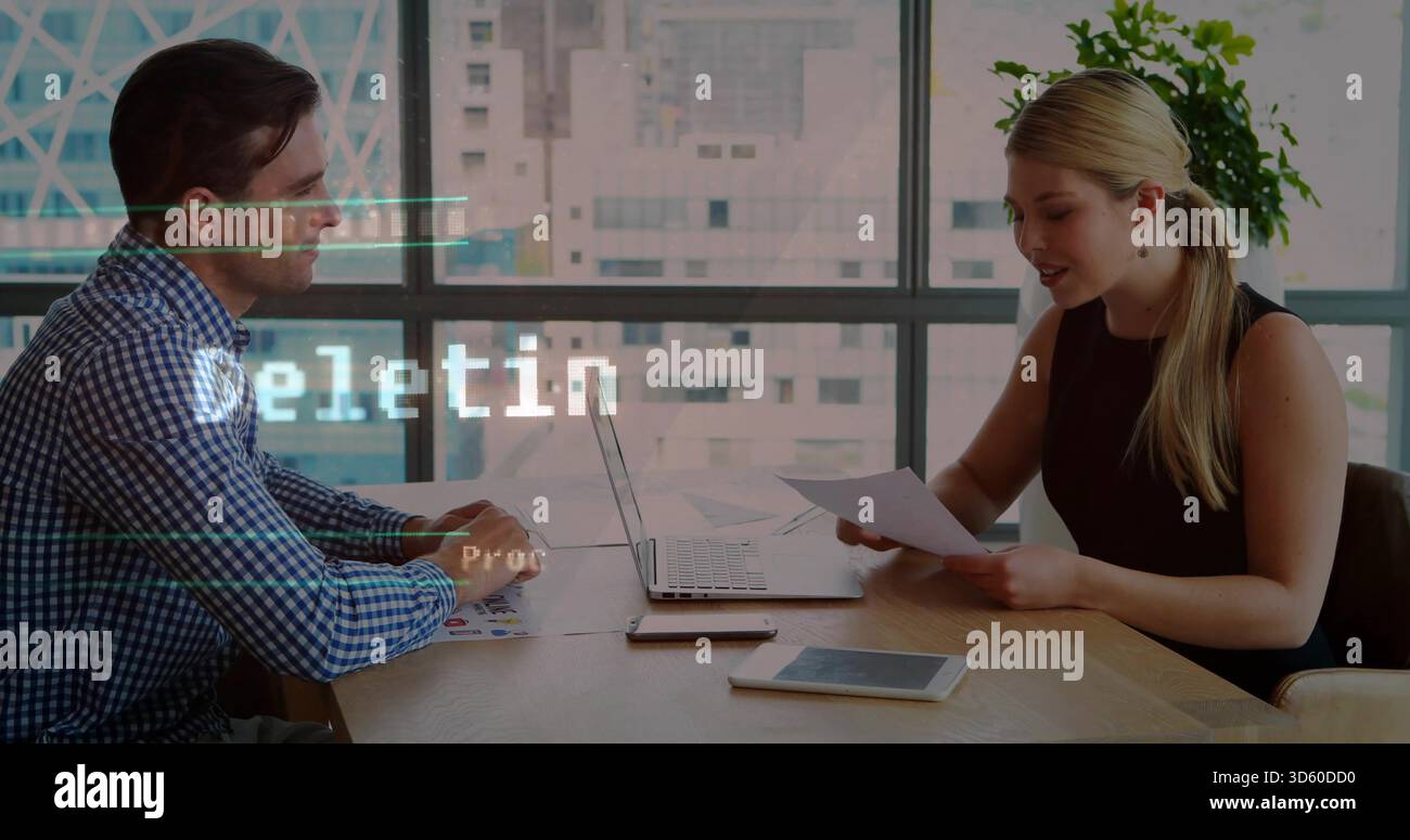 Camicia-uomo-blu e abito-donna-nero che recensiscono i documenti al tavolo delle riunioni con un laptop vicino alla finestra Foto Stock