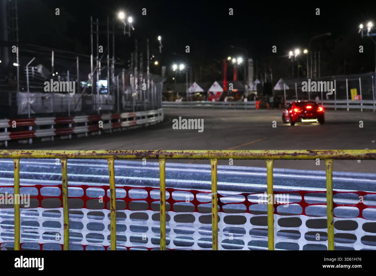Guida sportiva rossa emozionante con velocità sul circuito da corsa di notte. auto potente illuminata da una luminosa luce da stadio che mostra prestazioni elevate r Foto Stock