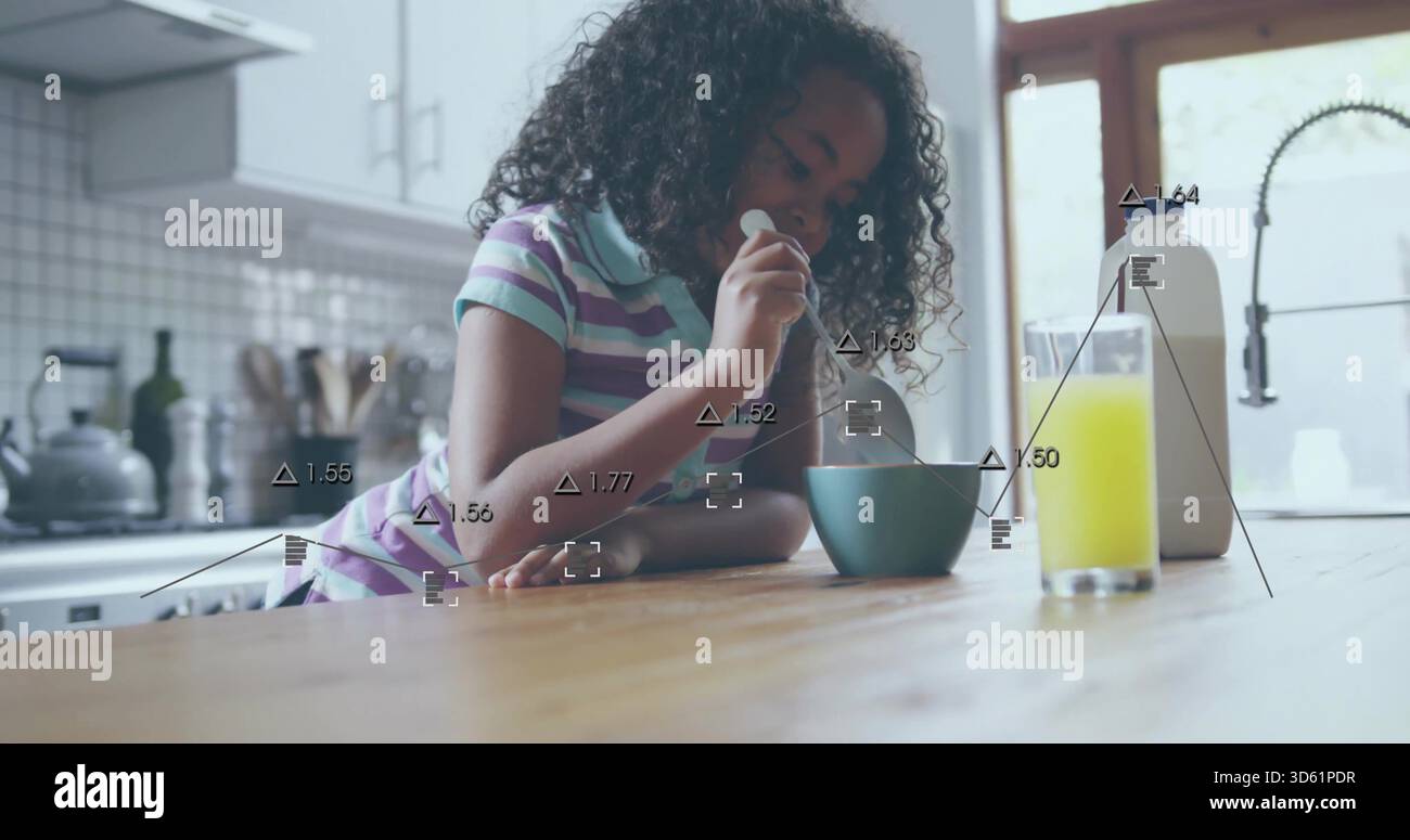 Mescola la bambina indossando una polo a righe pastello sul piano della cucina di casa con ciotola di tè e cucchiaio Foto Stock
