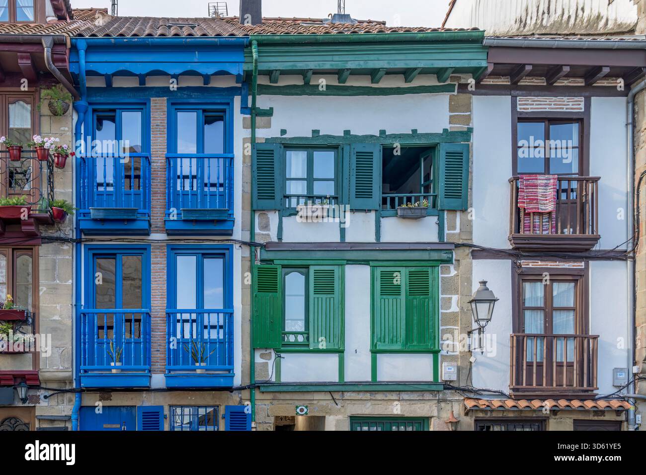 Edifici tradizionali colorati, balconi coperti blu verde marrone, facciate bianche, tapparelle in legno, architettura storica, stile basco Foto Stock