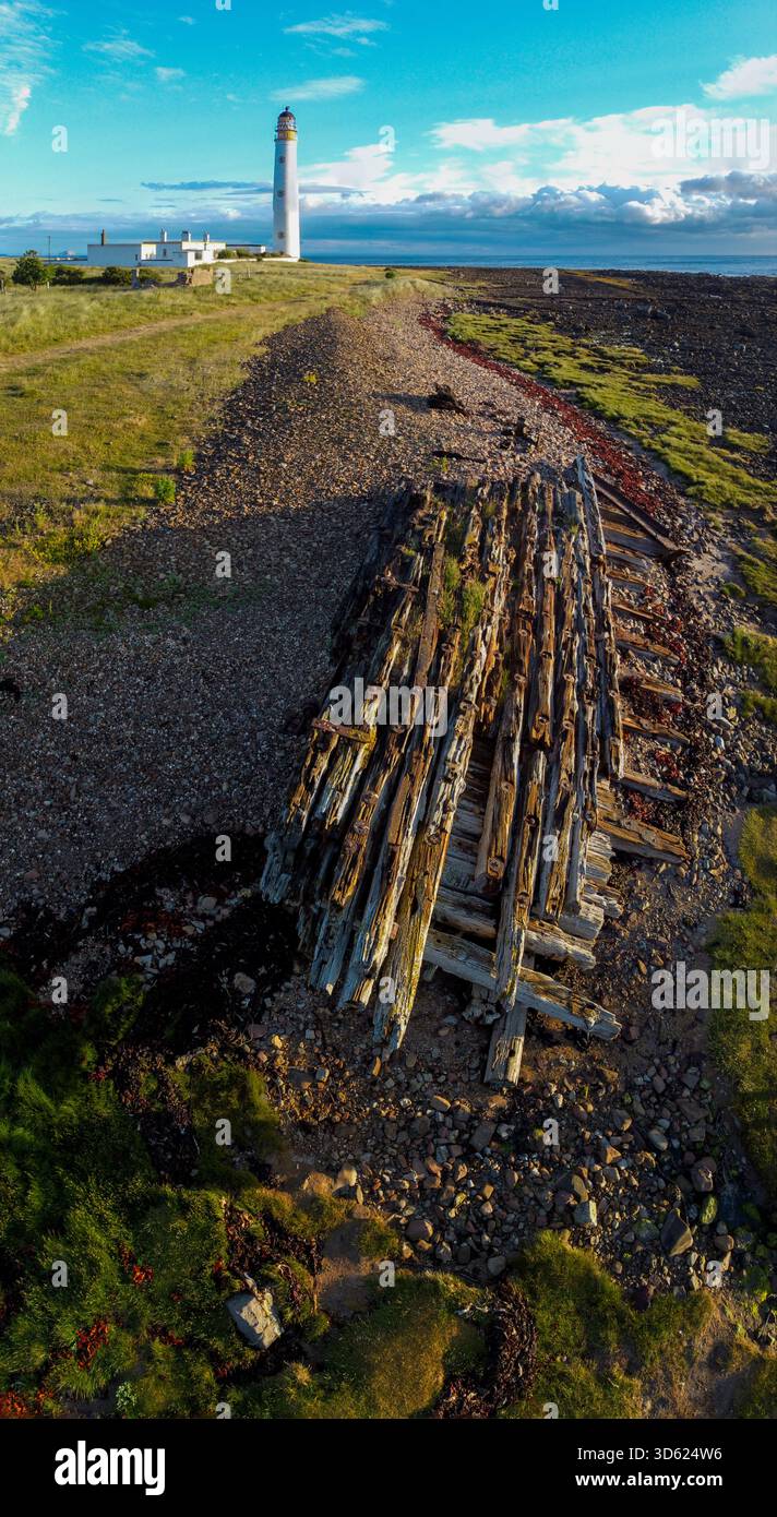 Vista aerea della costa del faro di Barns Ness con il sole mattutino che getta lunghe ombre dai resti del relitto sulla spiaggia di ciottoli Foto Stock