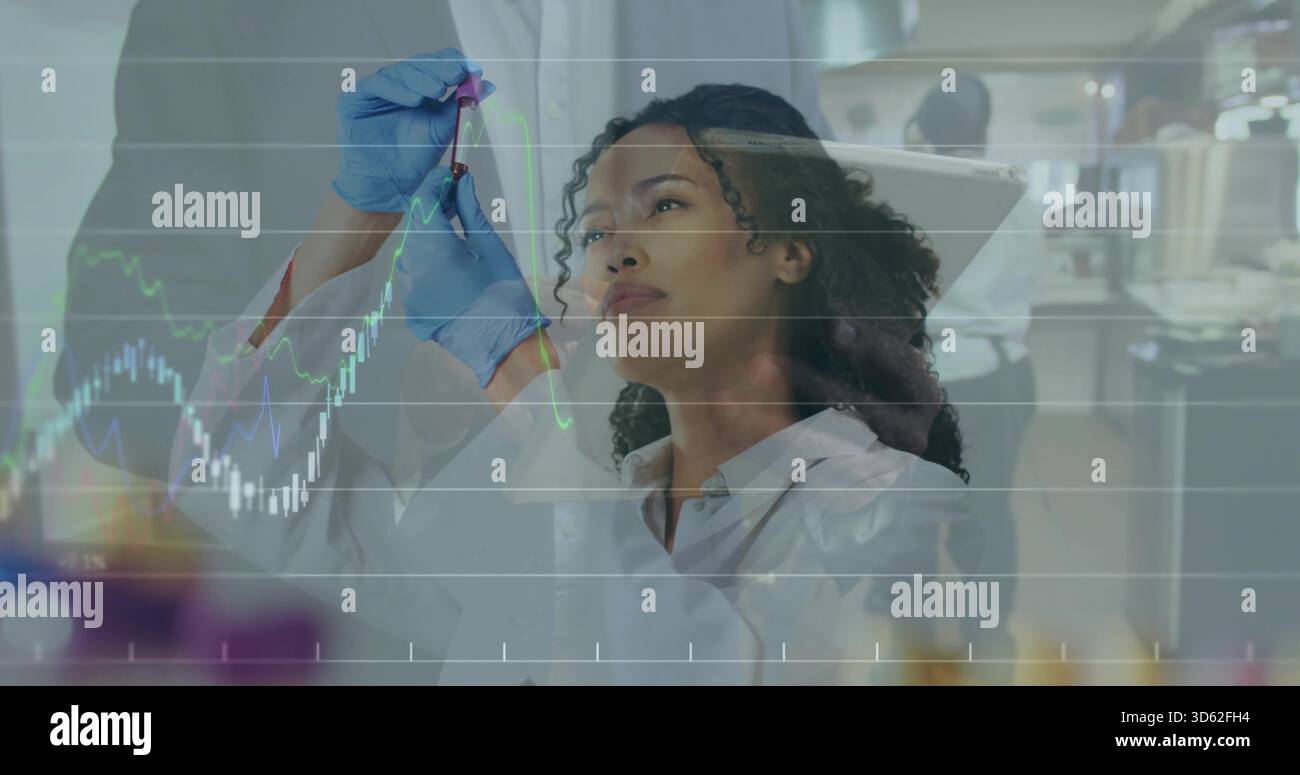 Scienziato che indossa un camice da laboratorio e guanti in nitrile blu che trattengono la fiala contro la luce in laboratorio con grafici Foto Stock