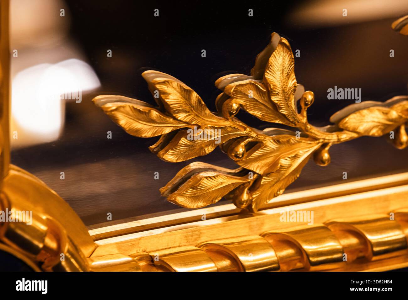 Il lussuoso motivo a foglia dorata decora una cornice a specchio, aggiungendo opulenza e fascino classico. Le ricche tonalità oro evocano un'eleganza antica, rendendo questo decoro Foto Stock