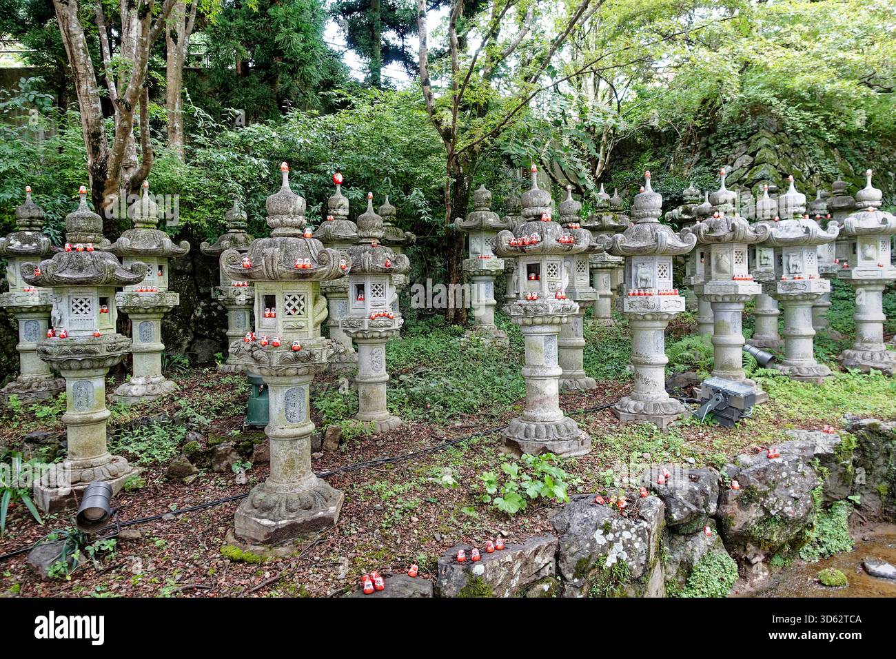 Molti piccoli ciondoli portafortuna Daruma collocati su vecchie tradizionali lanterne giapponesi in pietra al Tempio Katsuoji nel Parco Minoh, Giappone, Osaka, Minoh Foto Stock