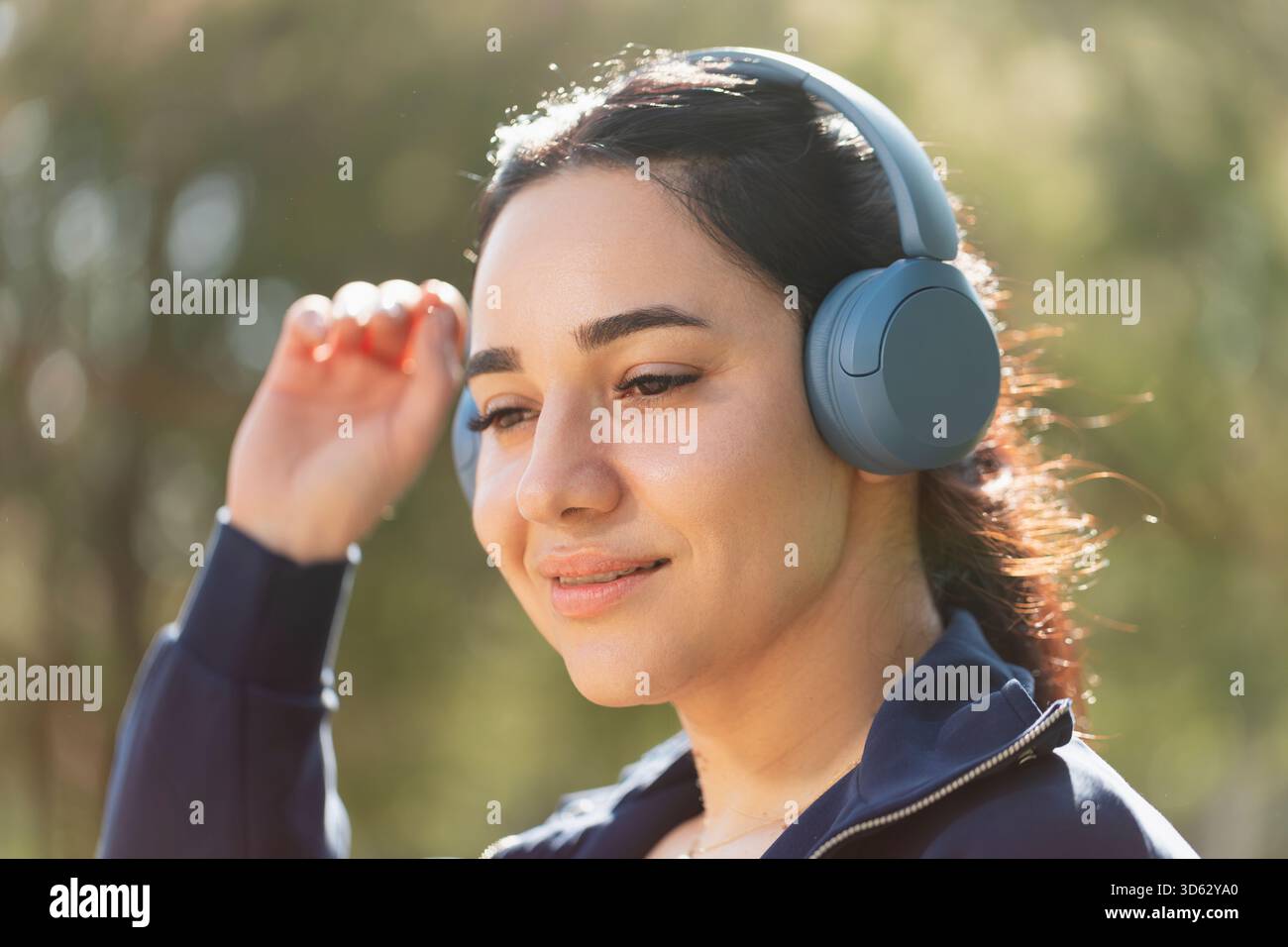 Una donna si rilassa e ama la musica che ascolta con le cuffie, mentre cammina e si fa esercizio nel parco Foto Stock