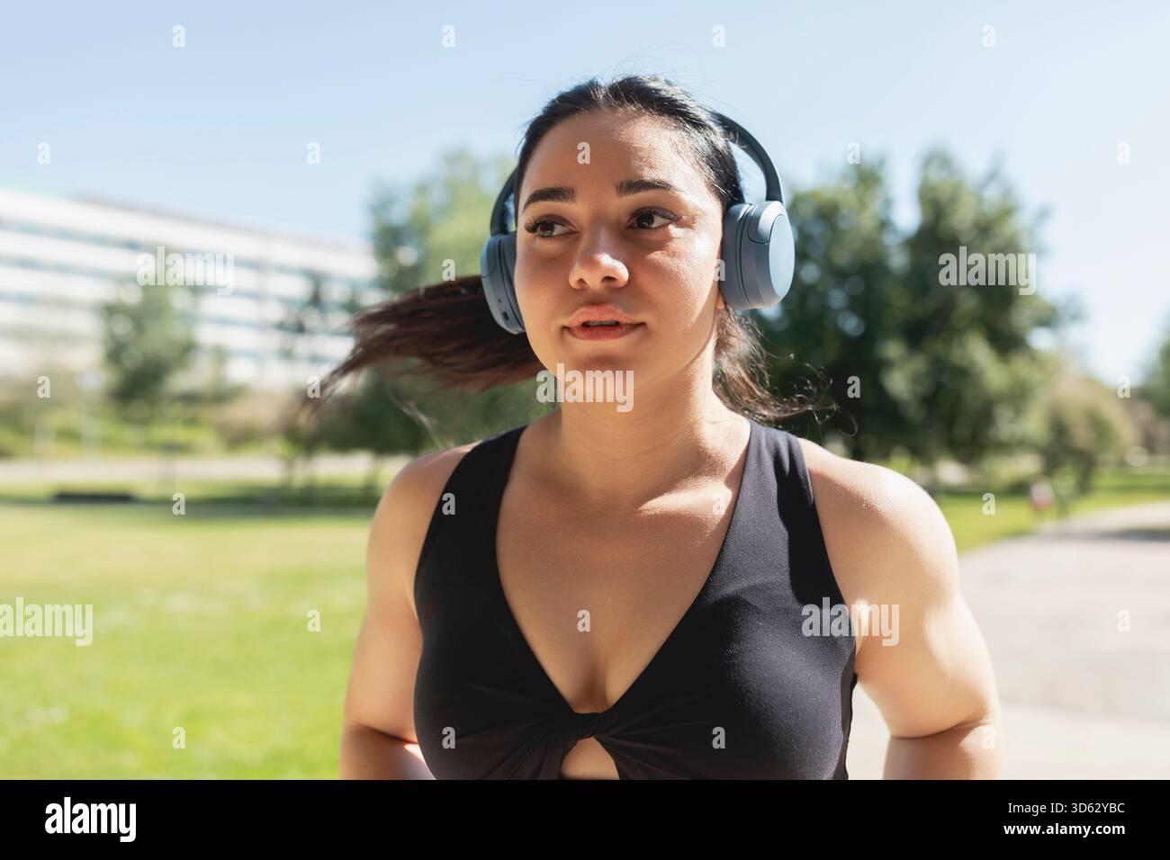 Una giovane donna che ascolta musica con le cuffie, mentre corre e si allena, Saragozza, Spagna Foto Stock