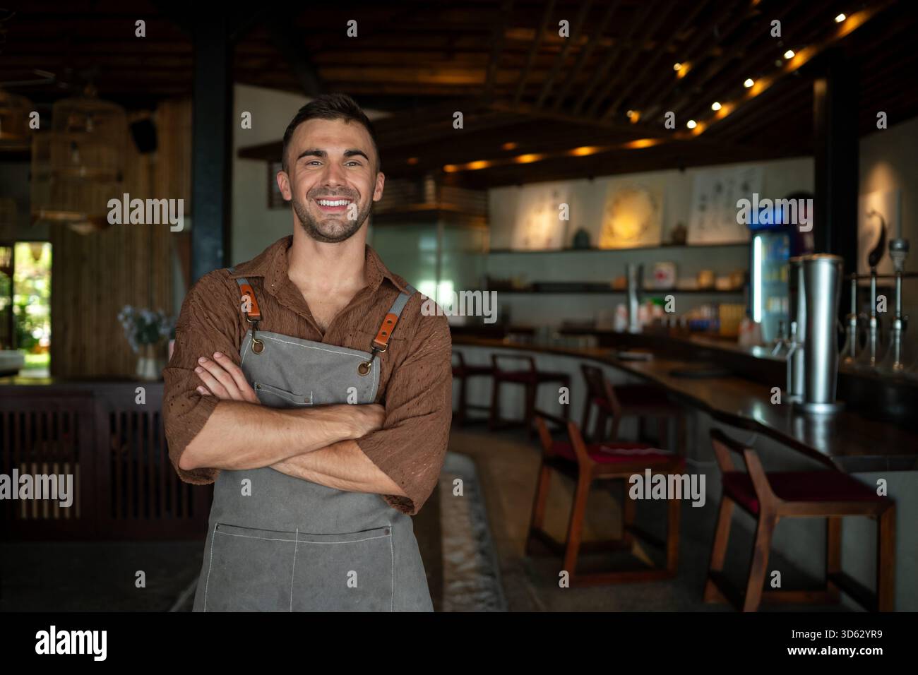 Caffè sicuro, proprietario di un ristorante in piedi con le braccia incrociate, che dà il benvenuto ai clienti al bar Foto Stock