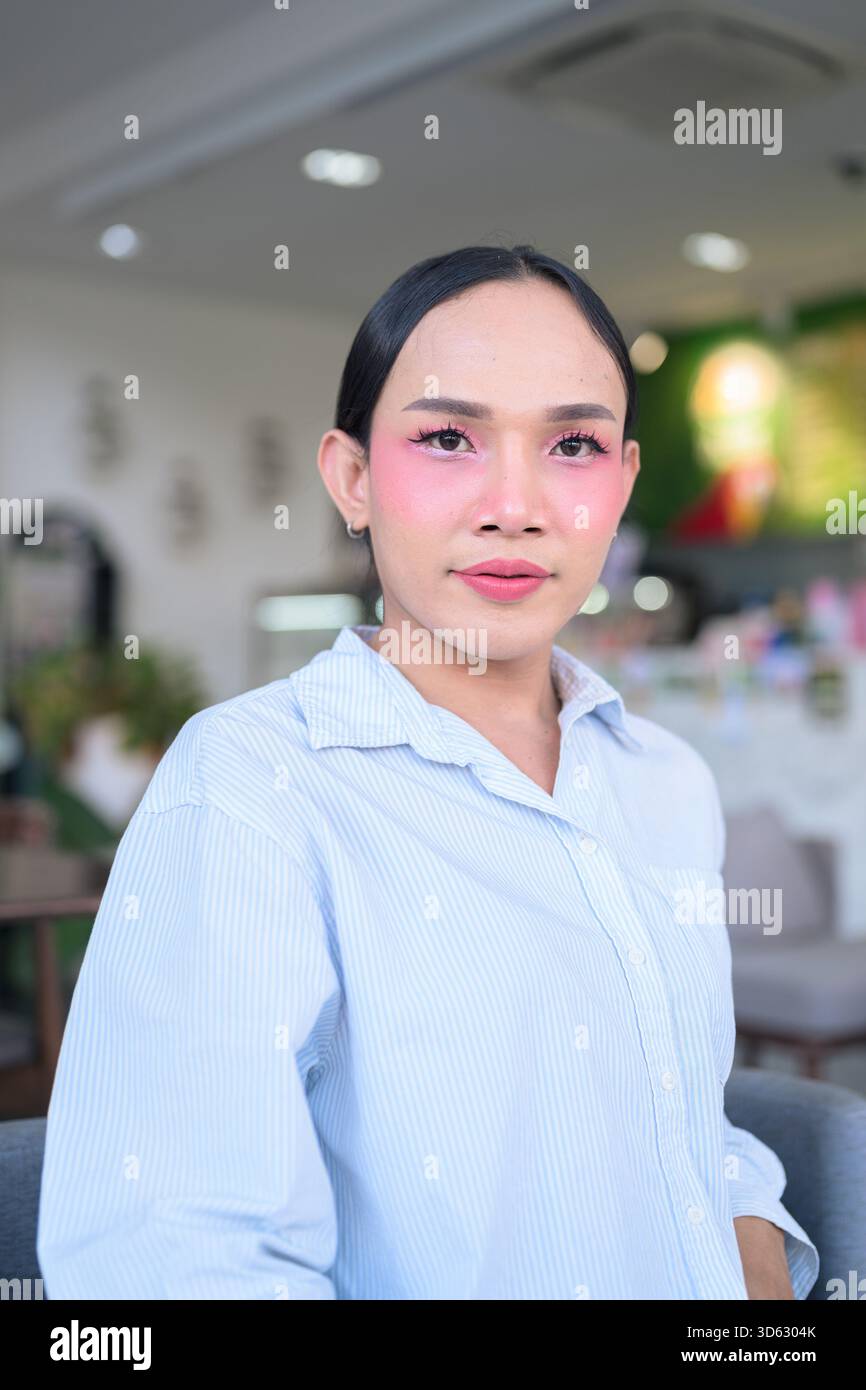 Ritratto di un giovane transgender thailandese con trucco e capelli lunghi. Concetto di espressione di genere, orgoglio LGBTQ e inclusività che mostra autententi Foto Stock