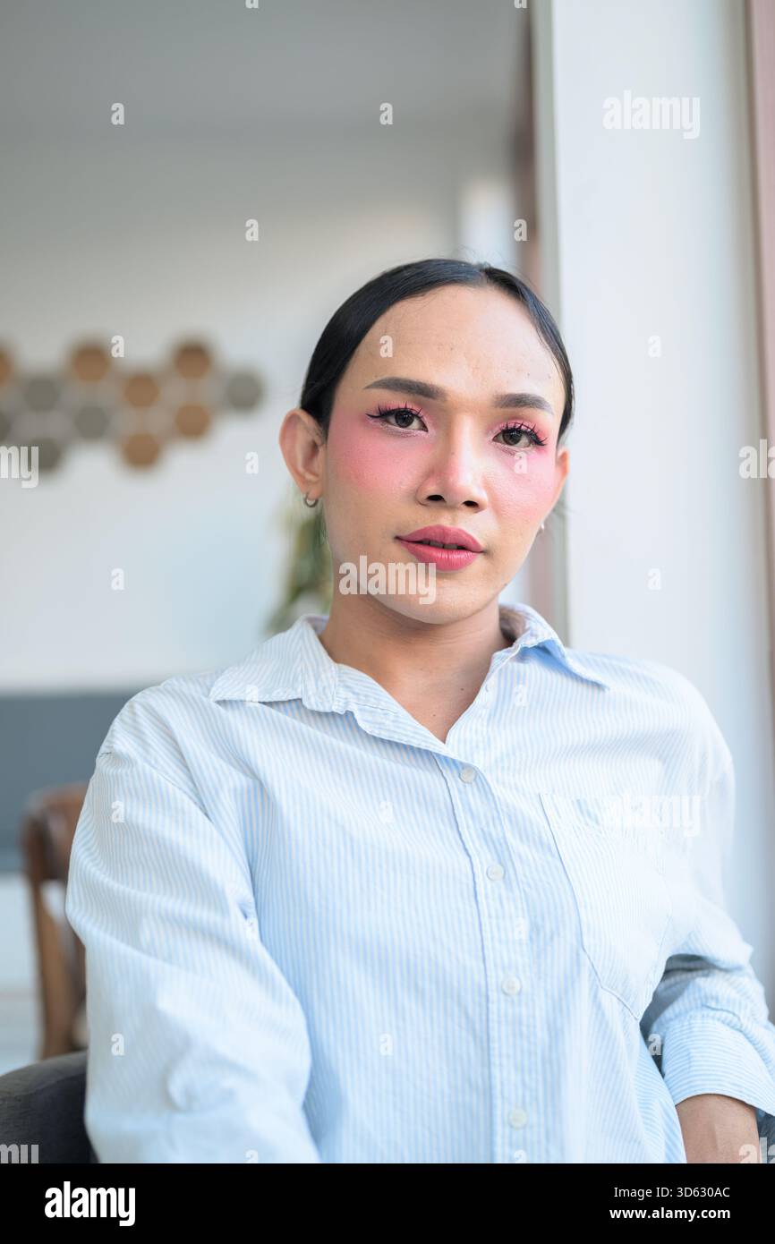 Ritratto di un giovane transgender thailandese con trucco e capelli lunghi. Concetto di espressione di genere, orgoglio LGBTQ e inclusività che mostra autententi Foto Stock