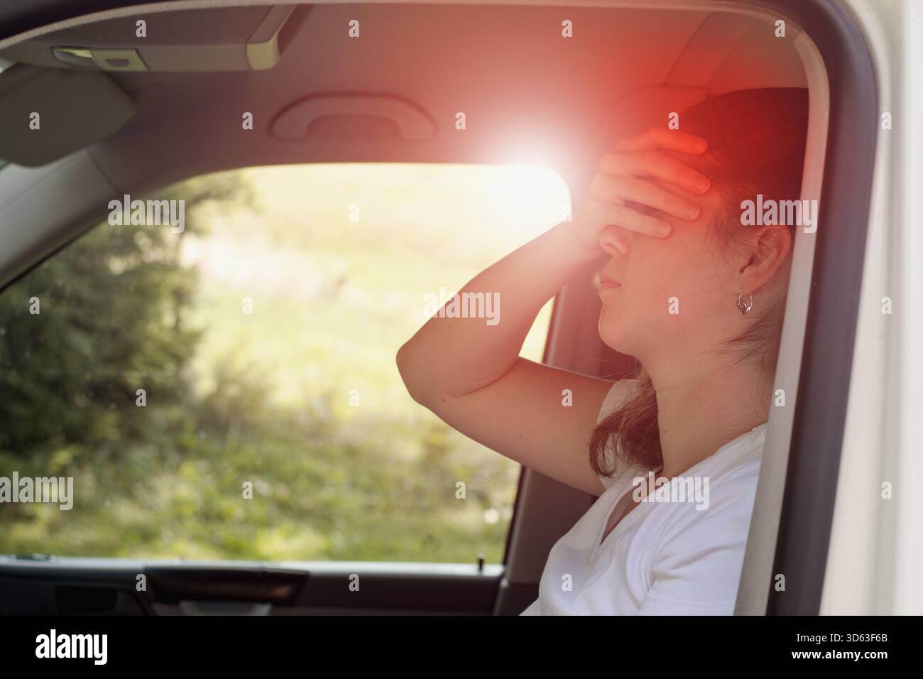 Donna seduta in auto che soffre di vertigini o vertigini o altri problemi di salute del cervello o dell'orecchio interno. Foto Stock