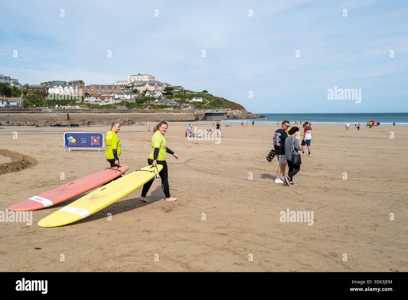 Due ragazze principianti del surf trascinano le loro tavole da surf al mare a Towan Beach in preparazione per una lezione di surf con Escape Surf School a Newquay Foto Stock