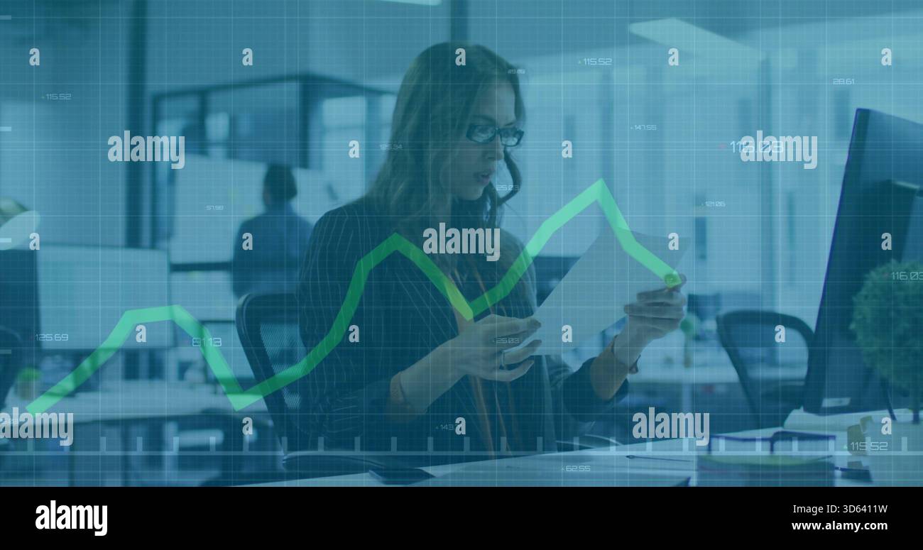 Revisione di documenti, donna in blazer e occhiali che studiano sovrapposizione di grafici con monitor in ufficio aperto Foto Stock