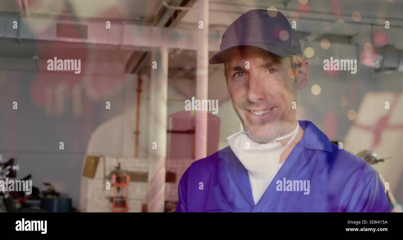 Meccanico sorridente in tuta e cappellino blu che lavora in garage, con maschera, moto, spazio per copiare Foto Stock