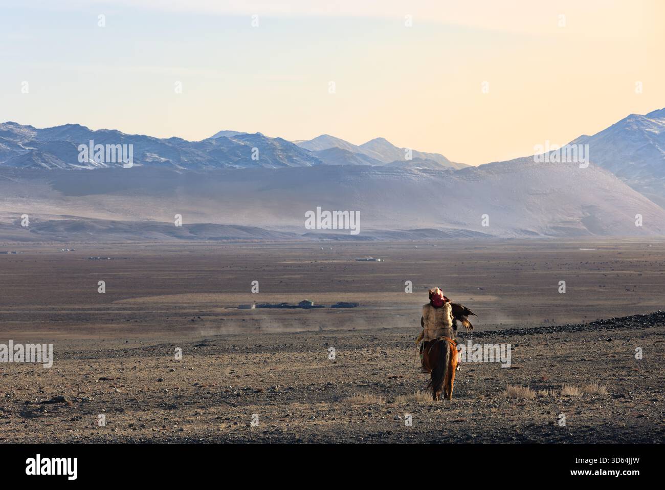 Un cacciatore di aquile kazako a cavallo dimostra la secolare tradizione della falconeria che definisce la cultura kazaka mongola nei monti Altai. Foto Stock