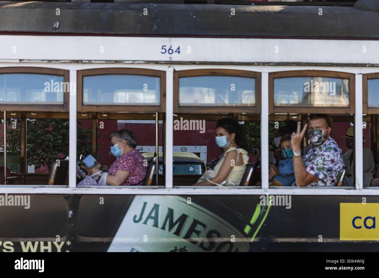 Lisbona, Portogallo - 18 luglio 2020: I passeggeri che indossano le maschere viaggiano sullo storico tram 564, con i suoi esterni scuri che contrastano con gli interni luminosi Foto Stock
