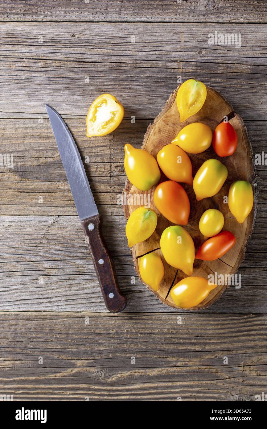 Vari pomodori maturi colorati su sfondo di legno. Cottura a partire da pomodori gialli arancioni e ciliegini rossi. Vista dall'alto con spazio copiato Foto Stock